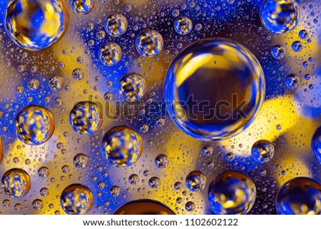 Water drops on glass with a gold and blue lighted background