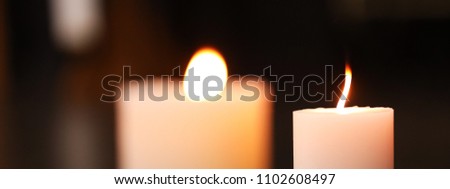 2 candles, front one in focus burning a beautiful flame against a black background. Perfect for ceremony, religious service, sadness and celebration.