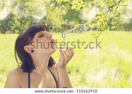 Young woman blow bubbles in the meadow