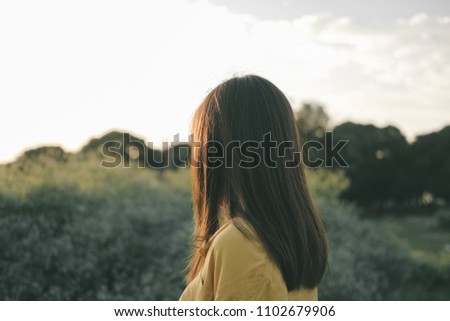 The girl wore jeans with a yellow shirt in the garden at sunset