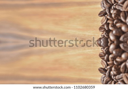 Fried coffee beans on a light brown wooden background.