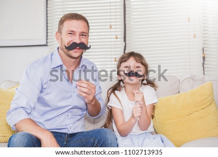 Portrait of dad and child daughter are playing and having fun together. Beautiful funny girl and daddy have mustache on sticks. Fun love family lifestyle single dad love father’s day holiday concept