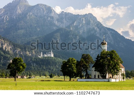 Schwangau, Germany. Scenic long shot view of St. Coloman Church, with world famous Schloss Neuschwanstein Castle in the background