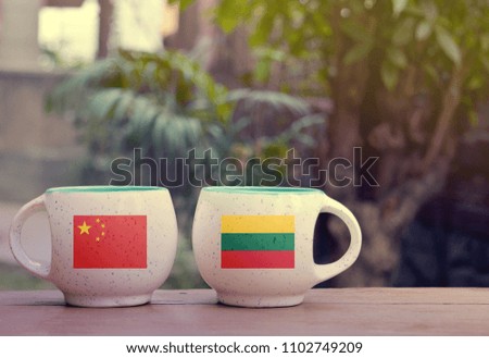 China and Lithuania Flag on two tea cups with blurry background