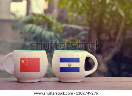 China and El Salvador Flag on two tea cups with blurry background
