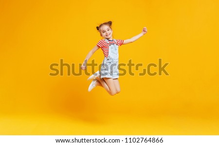 funny child girl jumping on a colored yellow background Royalty-Free Stock Photo #1102764866