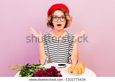 Indoor image of shocked elegant woman in french clothes style looks with wide eyed expression. Red beret . Pink background. 