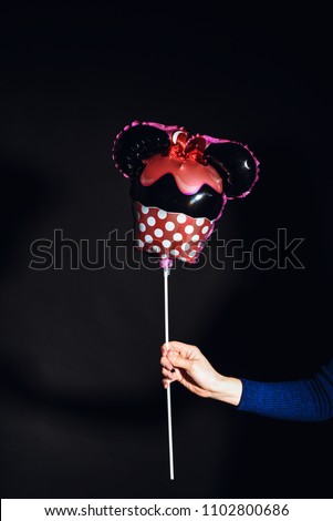 Mouse baloon in the hands on black background.