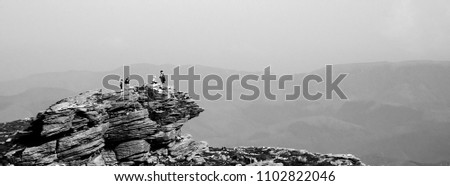 La Rhune mountain, French Basque Country. France. Family admiring misty view from the top. Holidays at nature background. Black and white photo.
