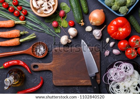Image on top of fresh vegetables, mushrooms, cutting board, oil, knife