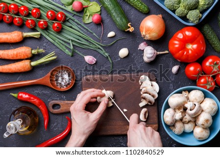 Picture on top of fresh vegetables, mushrooms, cutting board, oil, knife, hands of cook