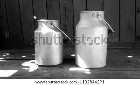 vintage aluminum milk cans on wooden floor on old wooden boards background. black and white photo