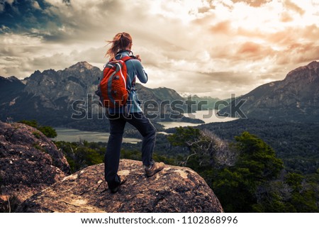 Tourist hiker with red backpack takes pictures of the valley with mountains and lakes. Patagonia, Argentina