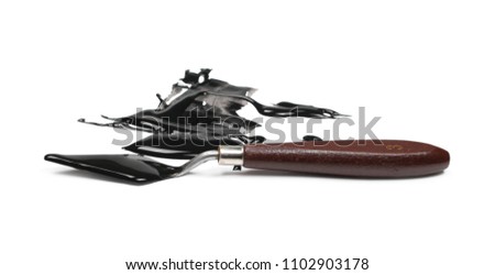 Spilled black watercolor puddle and painting spatula isolated on white background