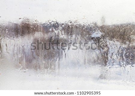 blurry view of russian village through frozen window in overcast winter day (focus on the ice surface on the glass)