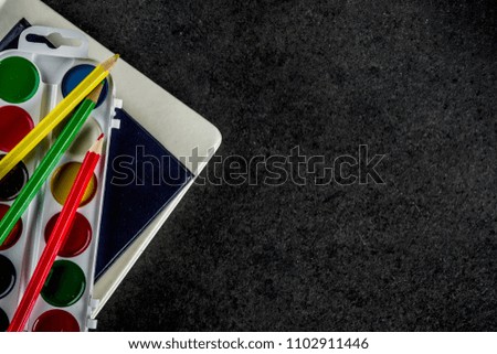 Back to school concept with books, alarm clock, color pencils, chalkboard background