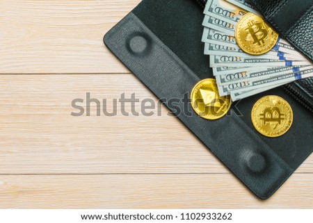 Crypto currency. Coins Bitcoin (BTC), banknotes one hundred dollars sticking out of a man's black leather purse on a wooden background.Blockchain.Intarnational currency.Top view.E-commerce.E-business.