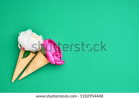 Ice cream cones with peony flower over green background. Summer concept. Copy space, top view