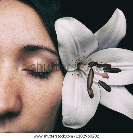 half of a girl's face with a white lily and closed eyes