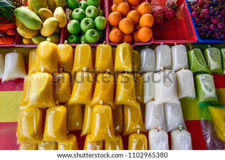 Refreshing cold tropical fruit juices in takeaway plastic wrappers sold in a hawker food stall at street market in Malaysia