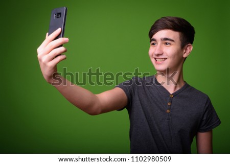 Young handsome Iranian teenage boy against green background