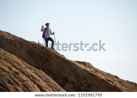 Picture of sportsman with backpack and walking sticks on hill