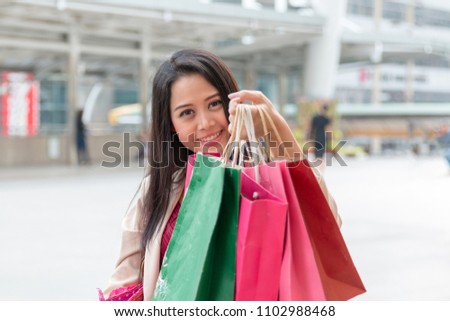 Young cheerful female with colourful shopping bags having fun and walking in the city street. Young beautiful female showing off her shopping bags. Sale. Young smiling woman showing shopping bag.