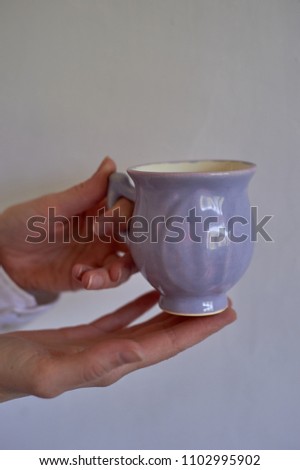 Gently purple bowl in the shape of a Bud, covered with icing. The skill of the ceramist.Hands in the frame