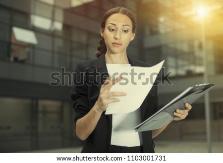 Woman is examining documents before signing outdoors.