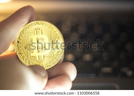A hand holding Golden Bitcoin - virtual money on blur background.