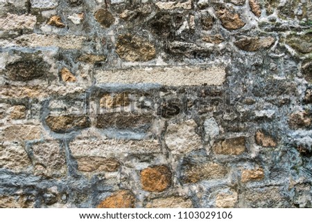 Ancient weathered wall constructed of natural cobblestone. Colorful horizontal image suitable for interior design, backdrop, wallpaper. Template background for advertising, products montage. 