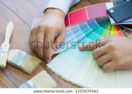 Man picking a color for her house walls, a professional painter and decorator is showing her color swatches