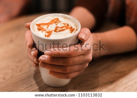 Picture of woman golding cup of coffee with caramel