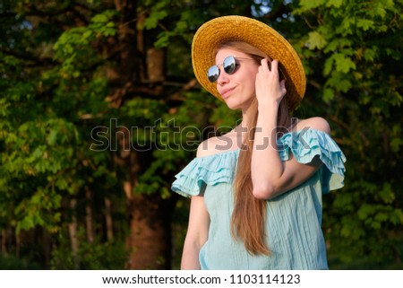 Redhead skinny girl in blue dress, mirror sunglasses and straw hat portrait in sunset light