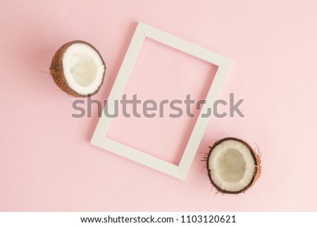 Coconut halves and white frame against pastel pink background minimal creative concept. Space for copy.