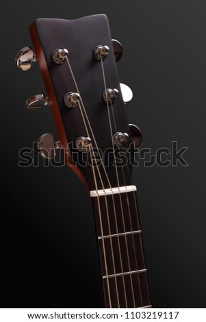 Guitar head with tuning pegs and neck with fingerboard, frets and nut. Details of the classic acoustic guitar