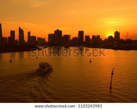 HO CHI MINH CITY, VIETNAM--MARCH 2018: Boats speed in the Mekong River with with sky scrapers and buildings in the background at sunset.