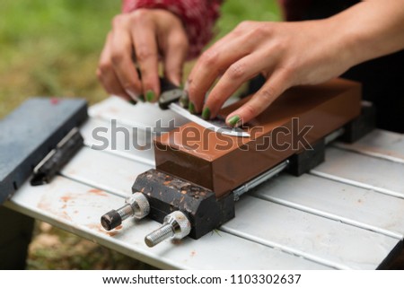 Woman sharpens a knife on a wet block outdoors