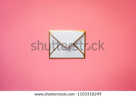 Single white envelope with golden ridges on blush pink background with copy space
