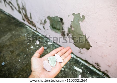 Hand holding crack color with mold house background.