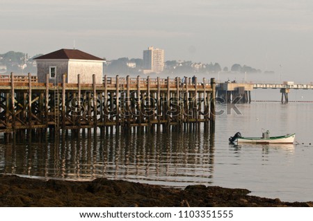 View of Portland, Maine from South Portland. Dock and boat house along with a small boat in the water.