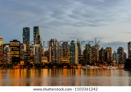 Embankment, boats, yachts and high-rise buildings of the modern city, the reflection of light in the water, the glowing windows of the night metropolis, the blue cloudy sky
