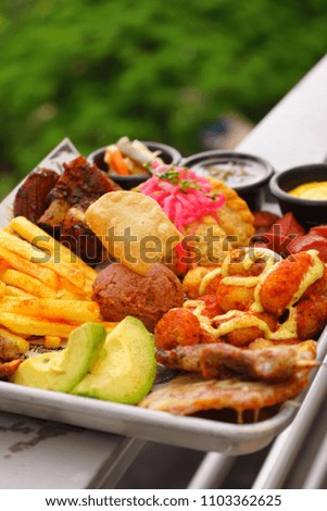 Tray of ribs, with fries, avocado, beans, pork sausage and sauces.