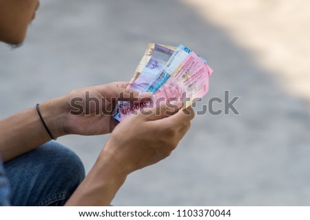 Asian young man counts money Royalty-Free Stock Photo #1103370044