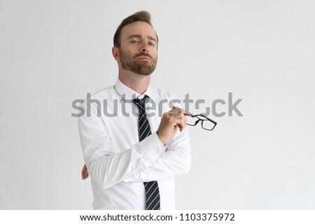Young arrogant business expert posing for camera. Vain serious Caucasian man with pained face expression holding glasses. Self importance and ego concept Royalty-Free Stock Photo #1103375972