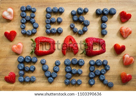 Happy Father's Day conceptual image with BEST DAD EVER inscription with Blueberries and Strawberries and many heart shaped strawberries on rustic cutting board.