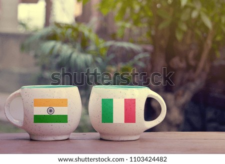 India and Italy Flag on two tea cups with blurry background