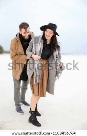 Happy caucasian woman and man wearing coats and scarfs standing in winter snow background. Concept of happy couple and positive emotions.