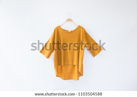 Minimal style.Yellow woman clothes is clothes hanger on white background.close up Royalty-Free Stock Photo #1103504588