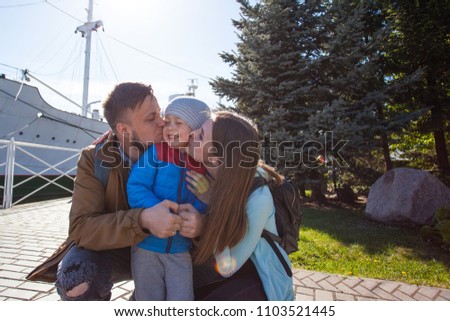 beautiful young couple kissing their sons on the cheeks